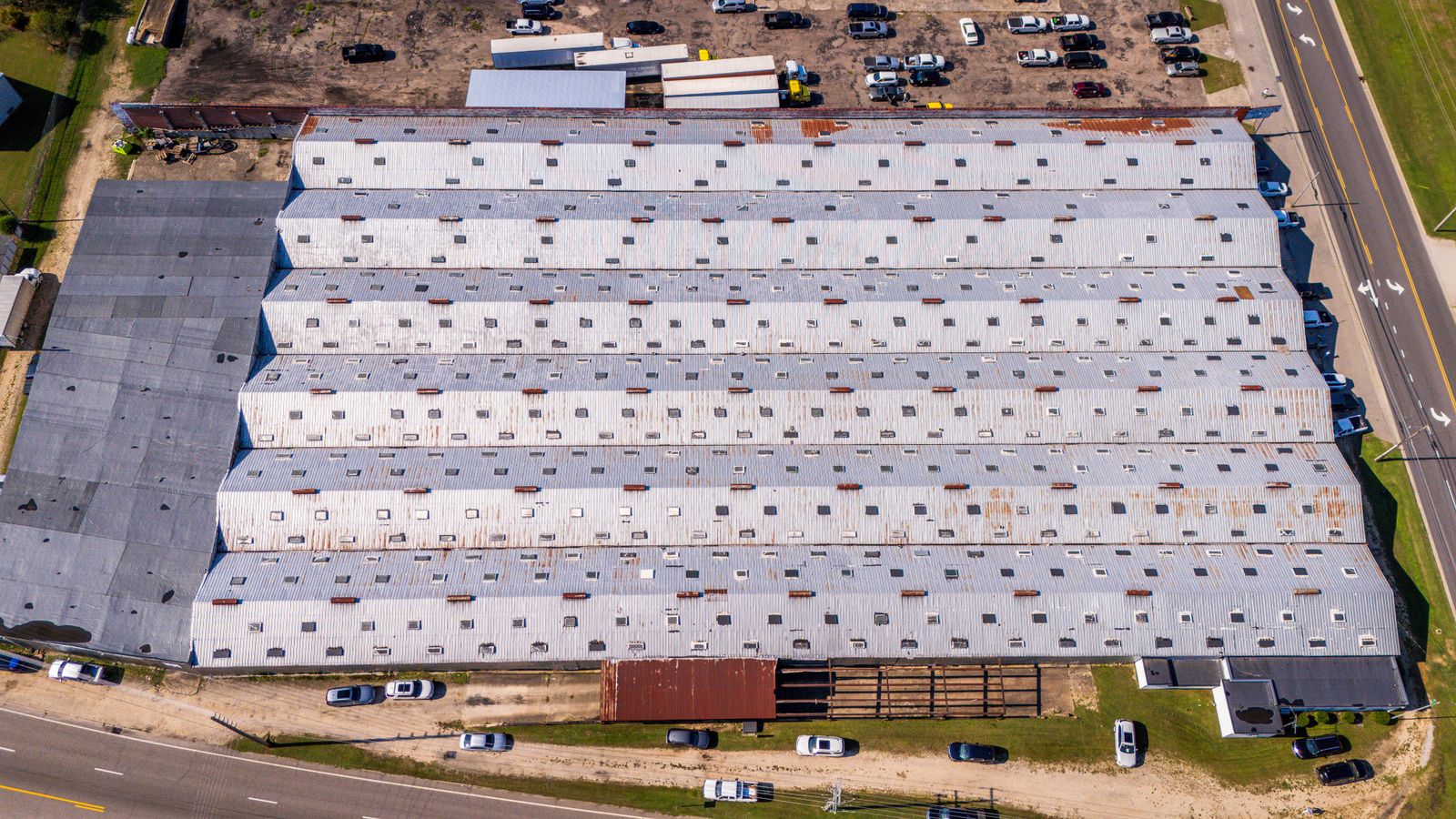 Vista aérea de una gran cubierta industrial de chapa con lucernarios y zonas de mantenimiento